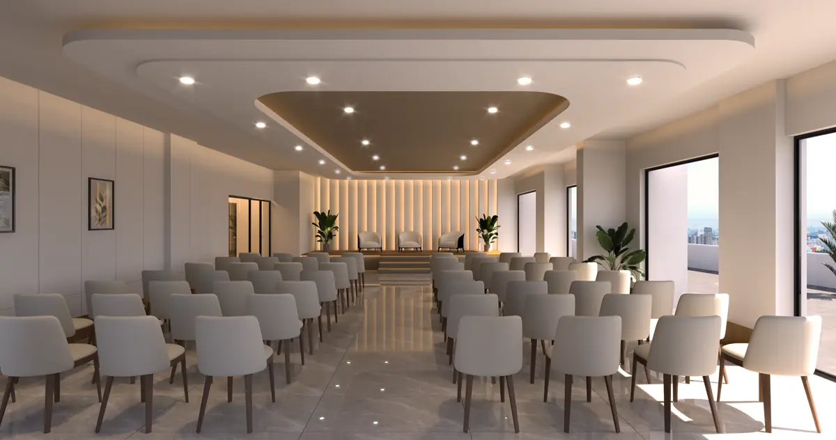 The multipurpose hall laid out with rows of seating under a coffered ceiling, with windows along one side.
