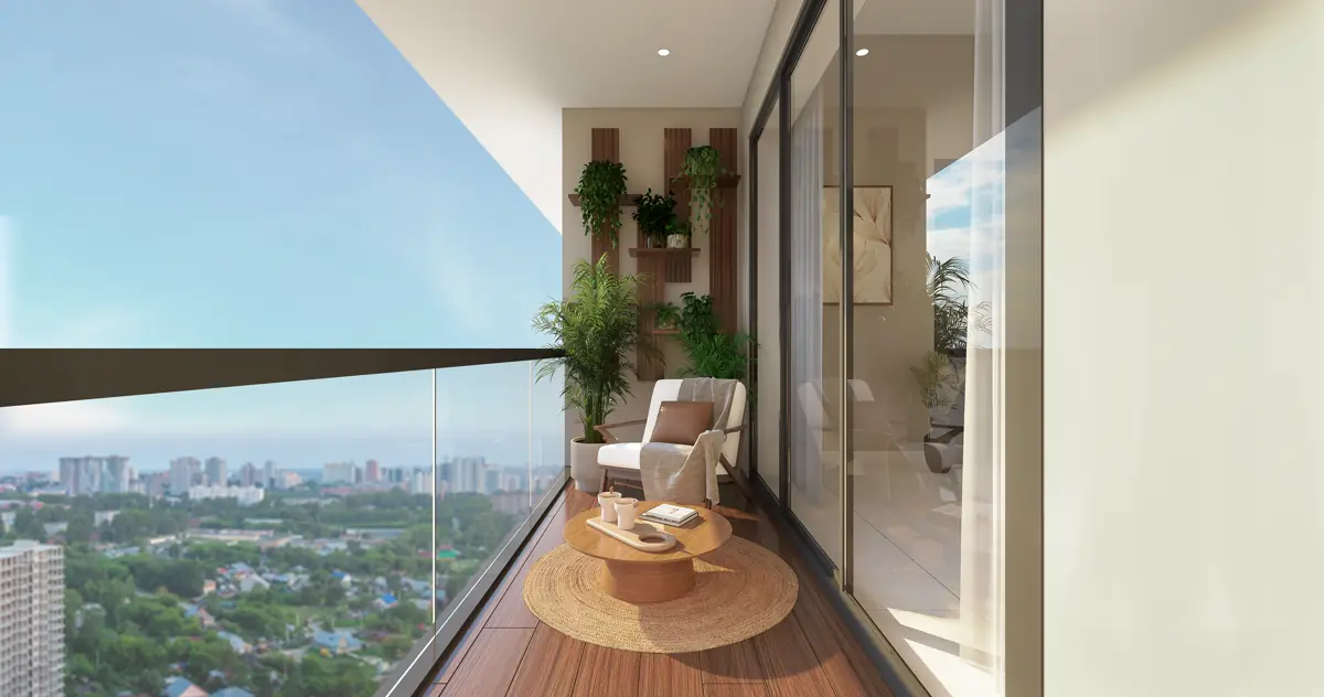 A balcony looking out over the low roofs and trees of central Trivandrum, with a chair, a low table and planting along the wall.